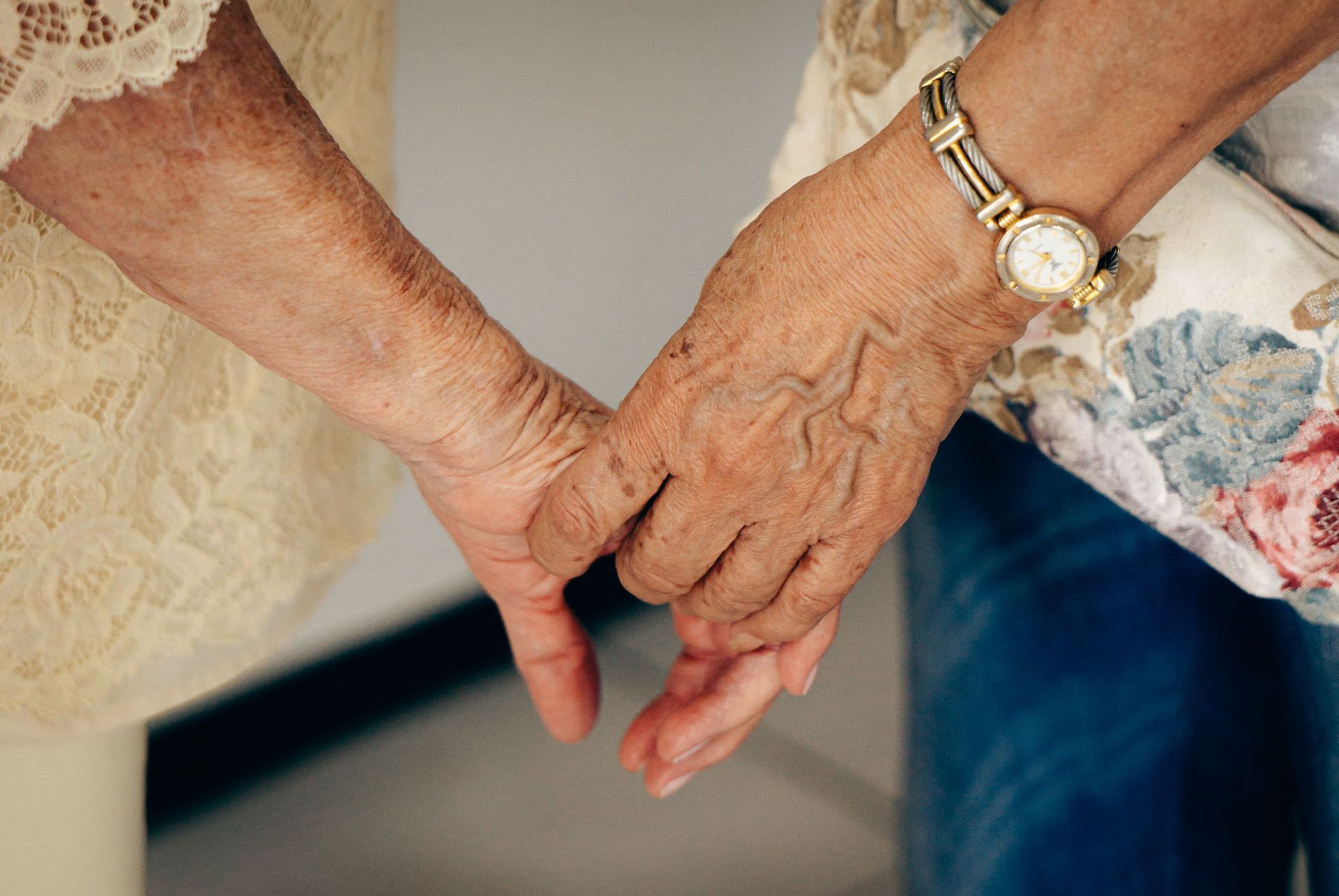 Close-up of elderly hands holding each other, symbolizing care and companionship.